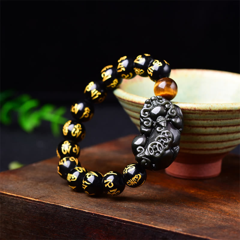 Obsidian PiXiu Rainbow Obsidian Wealth Bracelet – Carved black obsidian PiXiu bracelet on ceramic cup and wood