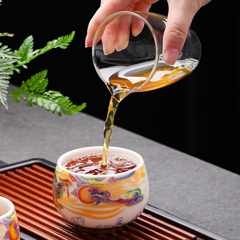 Dragon Phoenix Ceramic Teacup - Amber tea poured into phoenix cup on stone surface, ritual