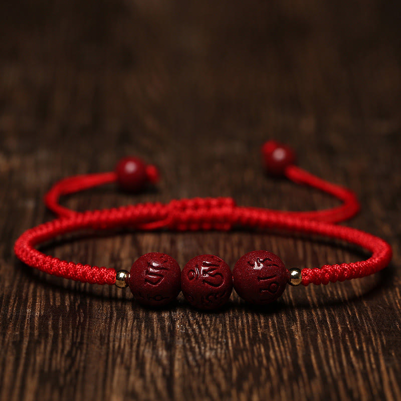 Cinnabar Om Mani Padme Hum Braided Bracelet – Carved mantra beads on red cord, low angle on wood, cinnabar