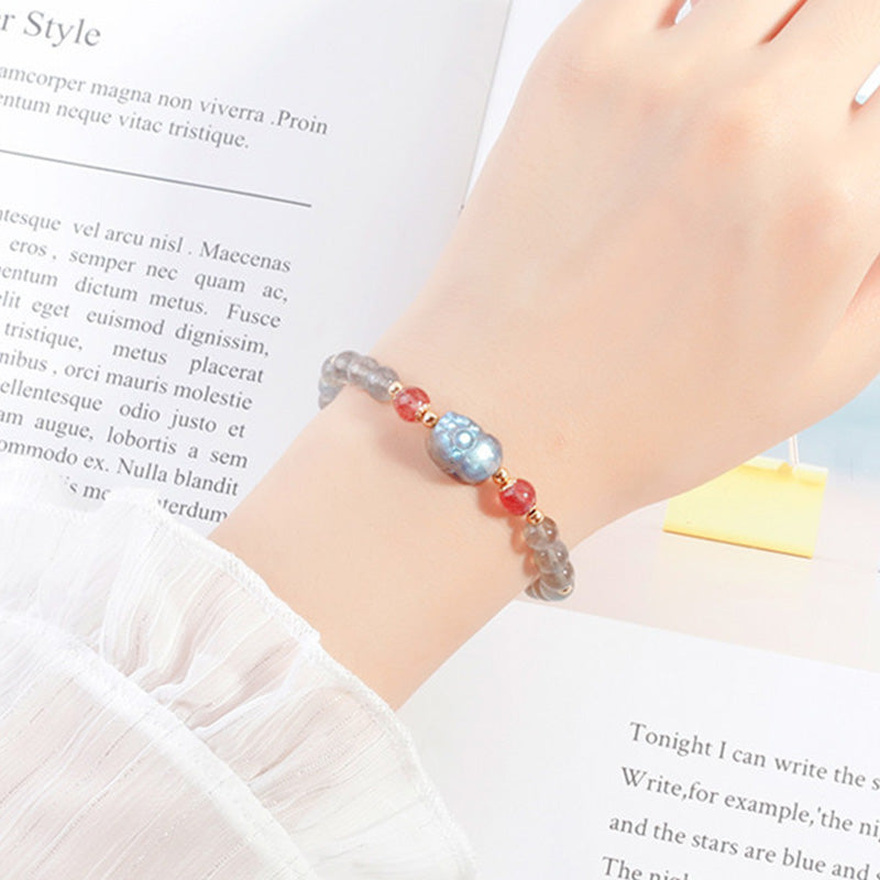 Moonstone PiXiu Bracelet – Wrist shot with white ruffled sleeve over magazine, feminine charm