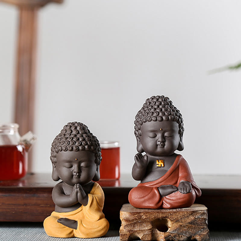 Small Buddha Purple Clay Decoration – yellow and orange variants on tea table with glass teaware bokeh, chachong tea pet cont