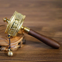 Sandalwood Tibetan Prayer Wheel – Golden brass mani wheel with Tibetan script on dark wood stand, three-quarter view, spir...