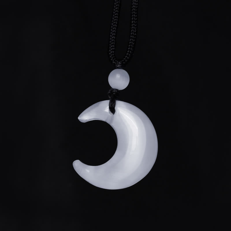Silver Sheen Obsidian Yin Yang Pendant - White selenite moon flat lay on black fabric, crystal necklace