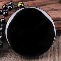 Bagua Dragon Phoenix Obsidian Pendant – Polished obsidian disc on rustic wood, natural healing