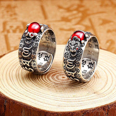 Feng Shui PiXiu Ring – Two silver rings with red stones on wood slice, antique Asian background