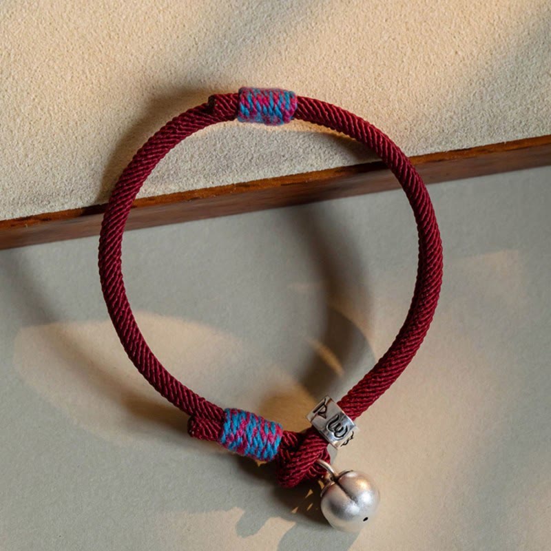 Om Mani Padme Hum Bracelet - Burgundy cord with blue magenta wrapping, silver bell and engraved bead flat lay