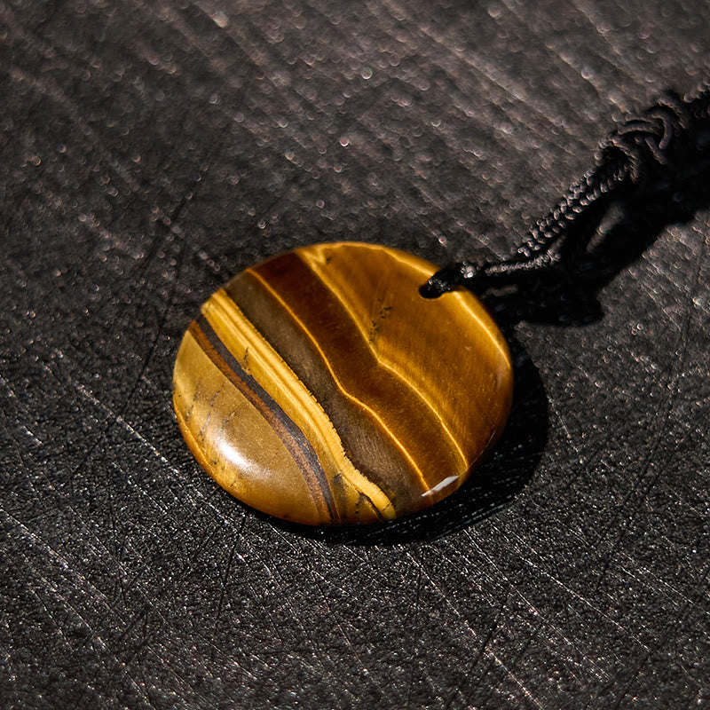 Yin Yang Crystal Necklace – Oval tiger eye gemstone with golden-brown striped banding on black cord, polished smooth chatoyan