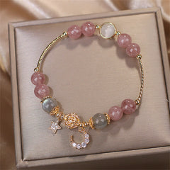 Strawberry Quartz Moonstone celestial charm bracelet with pink and gray-blue gemstone beads, gold moon and star pavé crystal charms in champagne gift box.