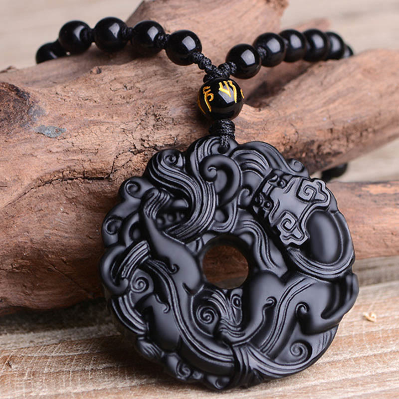 Black Obsidian Pixiu Pendant – Close-up on natural wood surface with black bead chain detail