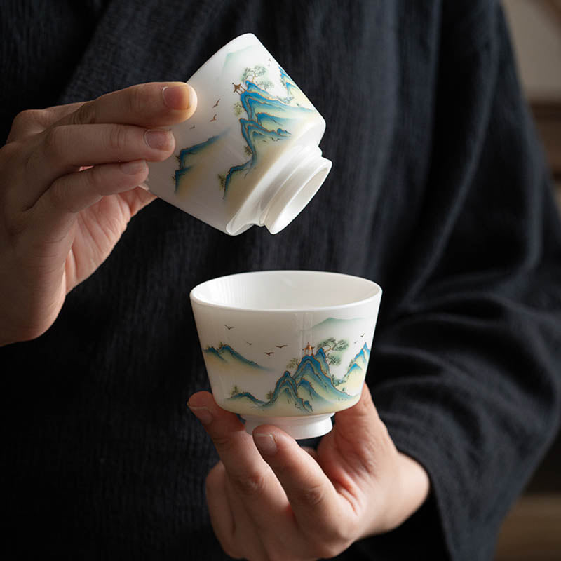 Ceramic Kung Fu Tea Cup – three-quarter view on dark wood, blue-green peaks with red pavilion, pine trees, serene