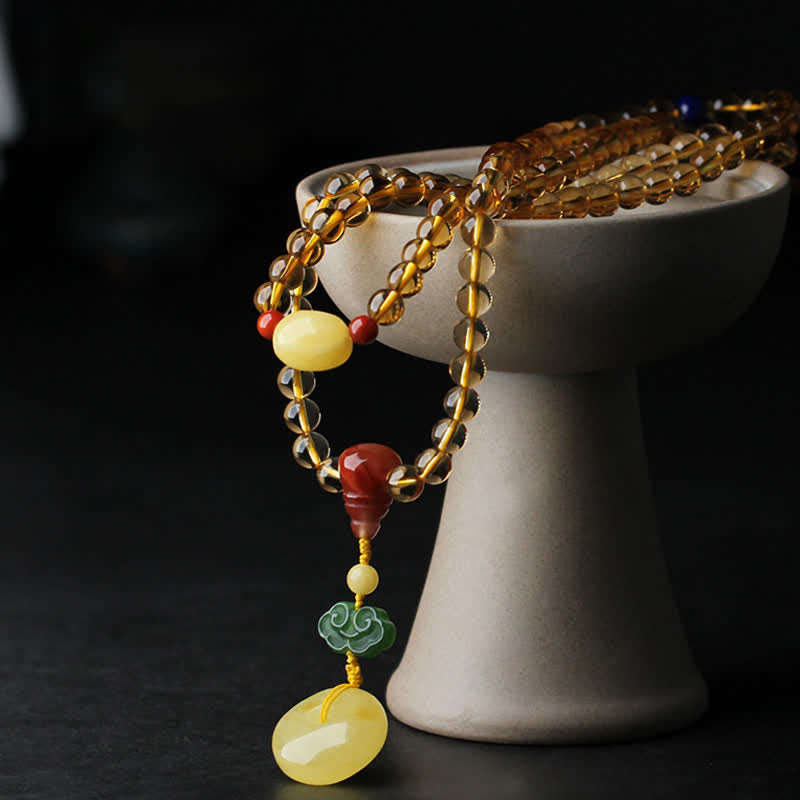 Citrine Mala Bracelet – Citrine beads on ceramic stand with amber peace buckle, dark background