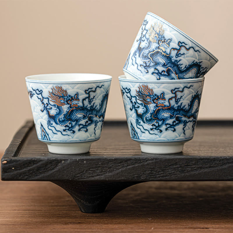 Blue & White Dragon Ceramic Teacup – three cups stacked on black tea tray, gold dragon accents, ceremonial