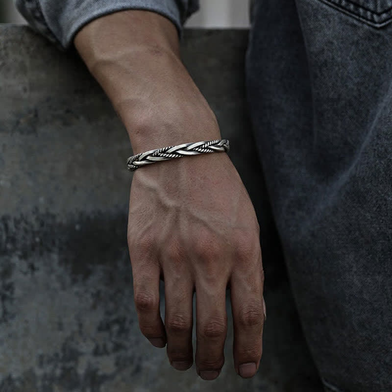 Viking twisted braided silver bracelet with double-helix rope twist oxidized antique finish worn on male wrist with gray shirt and blue denim in lifestyle setting