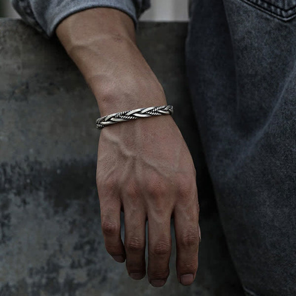 Viking twisted braided silver bracelet with double-helix rope twist oxidized antique finish worn on male wrist with gray shirt and blue denim in lifestyle setting