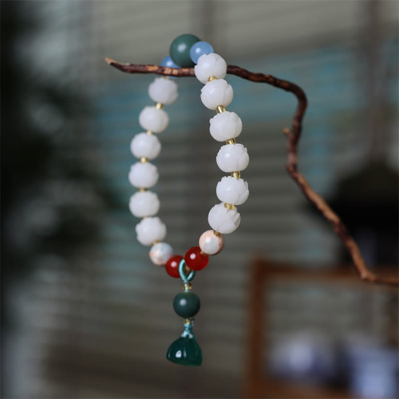 Carved Bodhi Seed Lotus Bead Peace Bracelet - hanging from twig with colorful accents, tranquility