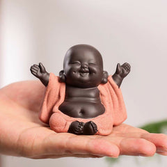 Laughing Buddha Purple Clay Maitreya Statue – miniature figurine cradled in palm, dark brown body and textured pink robe, joyful abundance charm