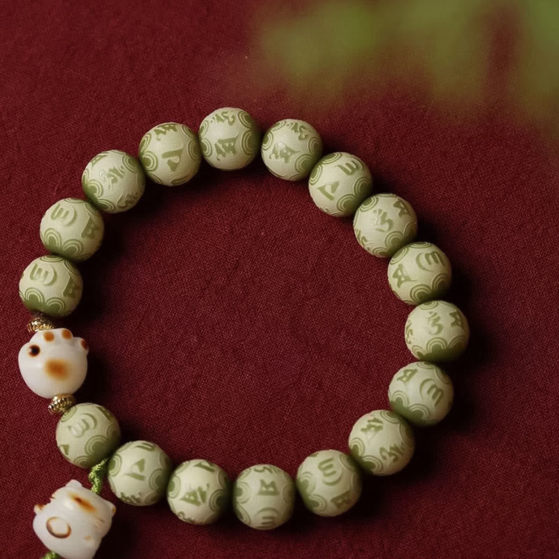 Bodhi Seed Bracelet – Green bodhi beads with cat figure charm and greenery bokeh background, natural stone bracelet