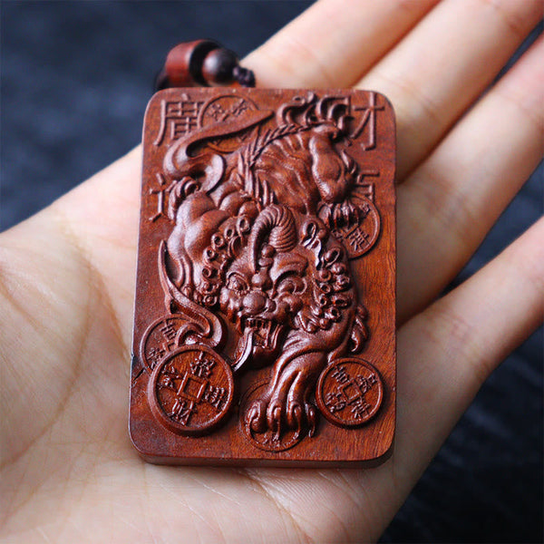 Lightning Struck Jujube Wood PiXiu – Hand holding carved wood PiXiu pendant scale