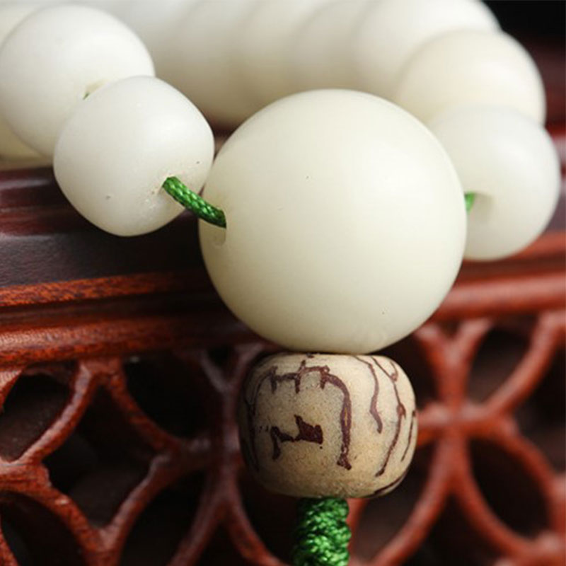 Bodhi Seed Lotus Mala - close-up of natural bodhi seed guru bead with brown veining on wood stand, texture