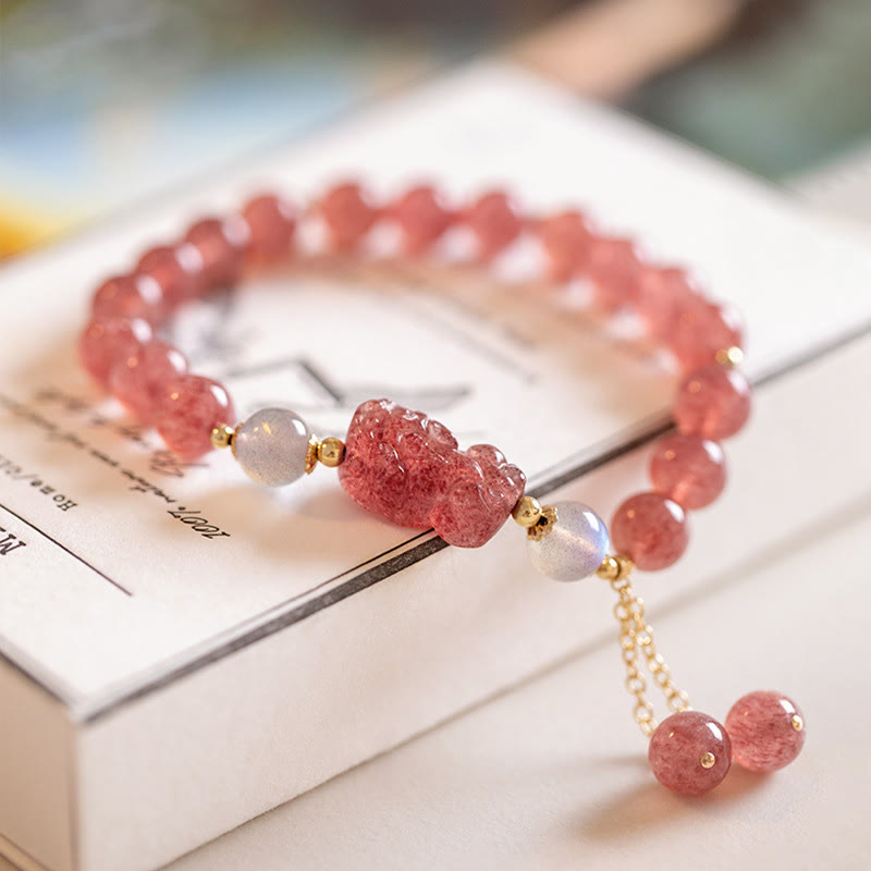 Strawberry Quartz Moonstone Bracelet – pink beads moonstone gold tassel on white book, love healing