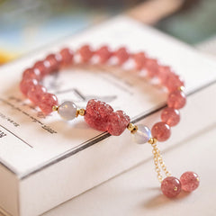 Strawberry Quartz Moonstone Bracelet – pink beads moonstone gold tassel on white book, love healing