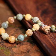 Bodhi Seed Green Sandalwood Lotus Bracelet – lotus beads on carved wood tray beside silk art, Artisan