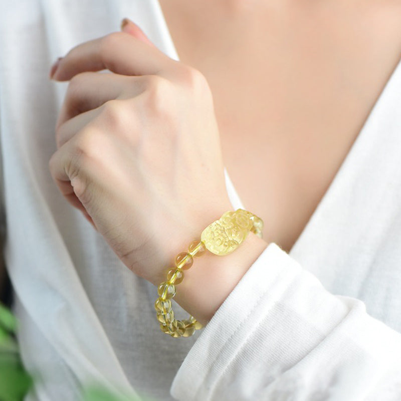 Citrine PiXiu Wealth Bracelet – worn on female wrist with white sleeve, glowing yellow crystal beads, feng shui wealth accessory