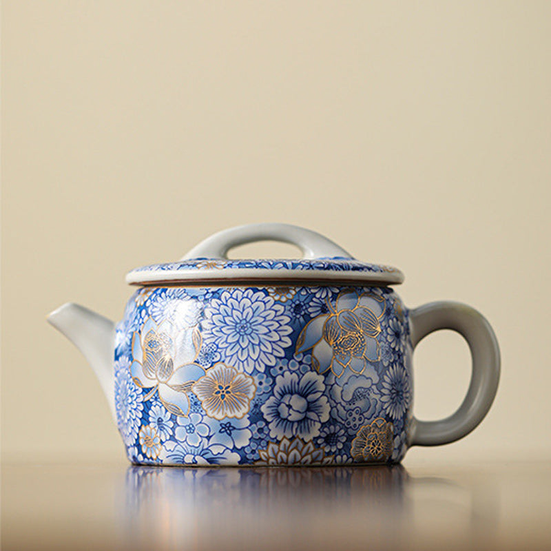 Lotus Chrysanthemum Ceramic Teapot - Frontal view on reflective surface with bridge lid, elegant