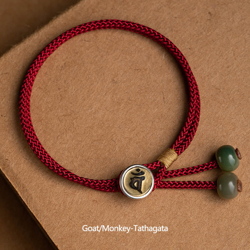 925 Silver Zodiac Natal Buddha Red String Bracelet on kraft paper, Goat and Monkey Tathagata Buddha mantra charm, two-tone gold and silver circular medallion, dark and light green jade beads, adjustable sliding knot