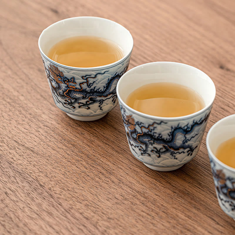 Blue & White Dragon Ceramic Teacup – three cups filled with amber tea on walnut wood, kung fu tea