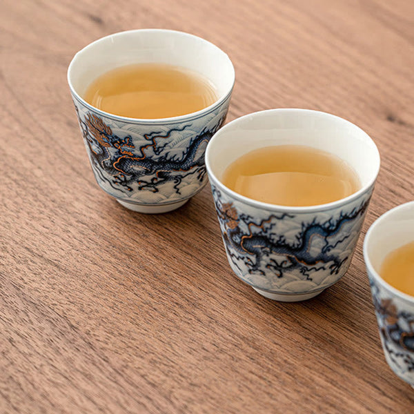 Blue & White Dragon Ceramic Teacup – three cups filled with amber tea on walnut wood, kung fu tea