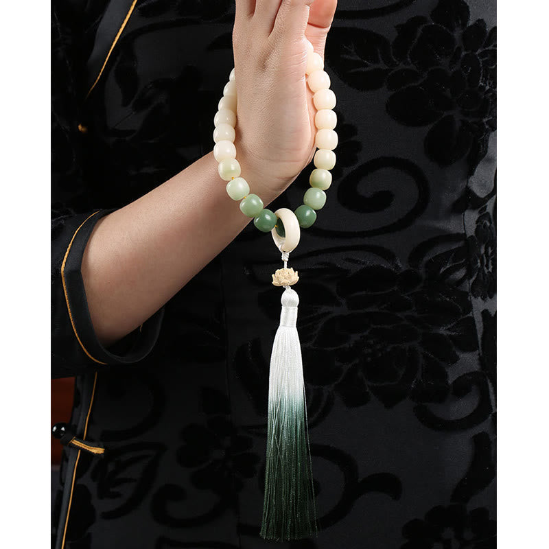 Bodhi Seed Lotus Wisdom Wrist Mala – Handheld mala cascading from hand, dark wood interior and green foliage, lotus and ombre tassel