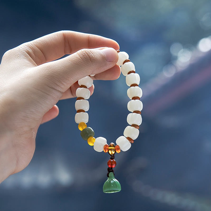 Bodhi Seed Lotus Bead Bracelet - hand-held with blue bokeh, serene outdoor styling