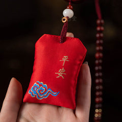 Red Sandalwood Car Hanging – Close-up of red embroidered peace pouch with gold cloud motif held on braided cord, car charm