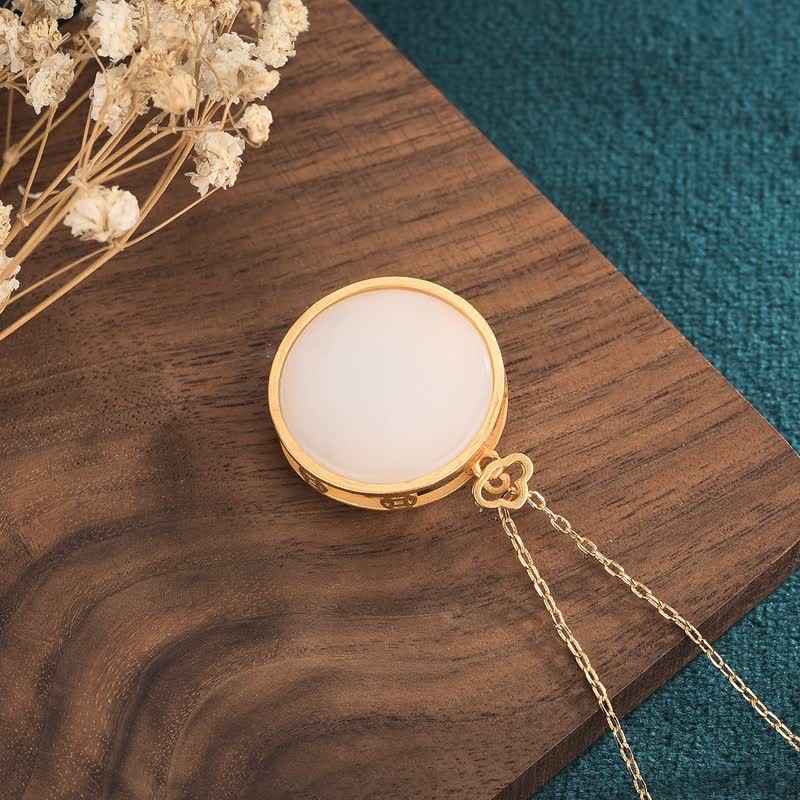 White Jade Koi Necklace – Pendant resting on display card with blessing pattern, Chinese lucky necklace