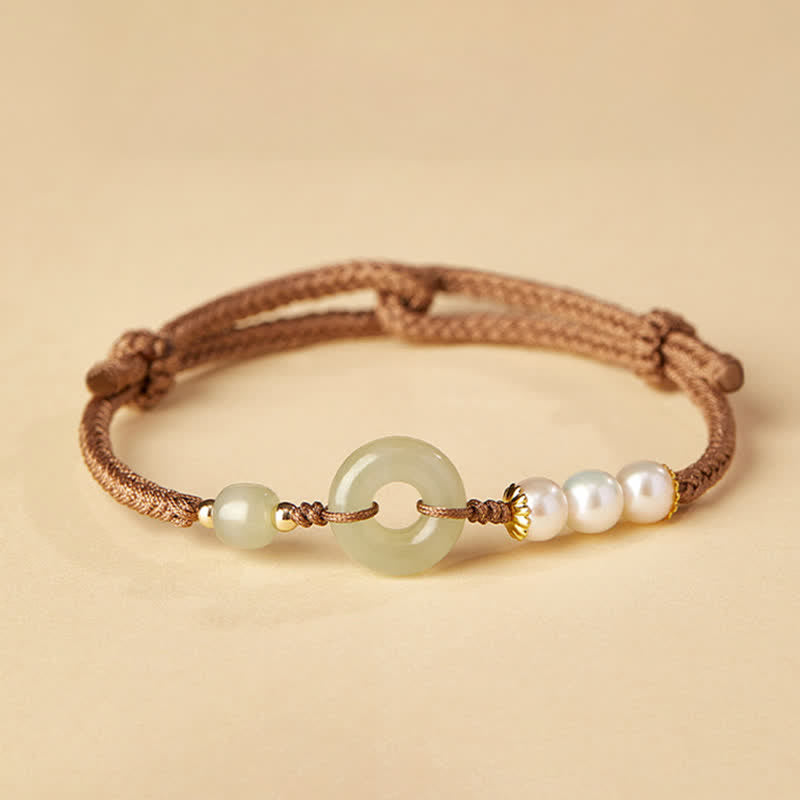 Hetian Jade Pearl Peace Buckle Bracelet – celadon jade bi disc with pearls and gold accents on brown cord, cream background studio shot