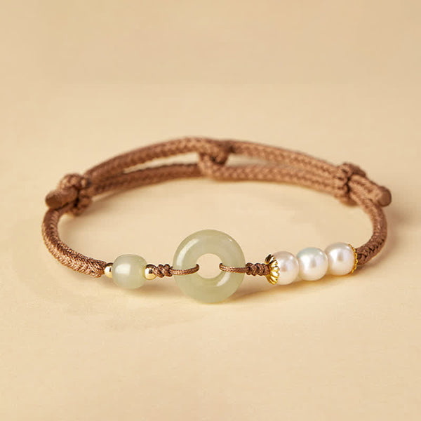 Hetian Jade Pearl Peace Buckle Bracelet – celadon jade bi disc with pearls and gold accents on brown cord, cream background studio shot