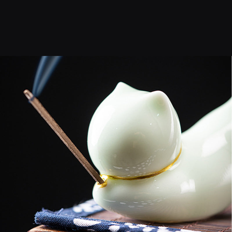 Celadon sleeping cat incense holder with gold collar, burning incense smoke