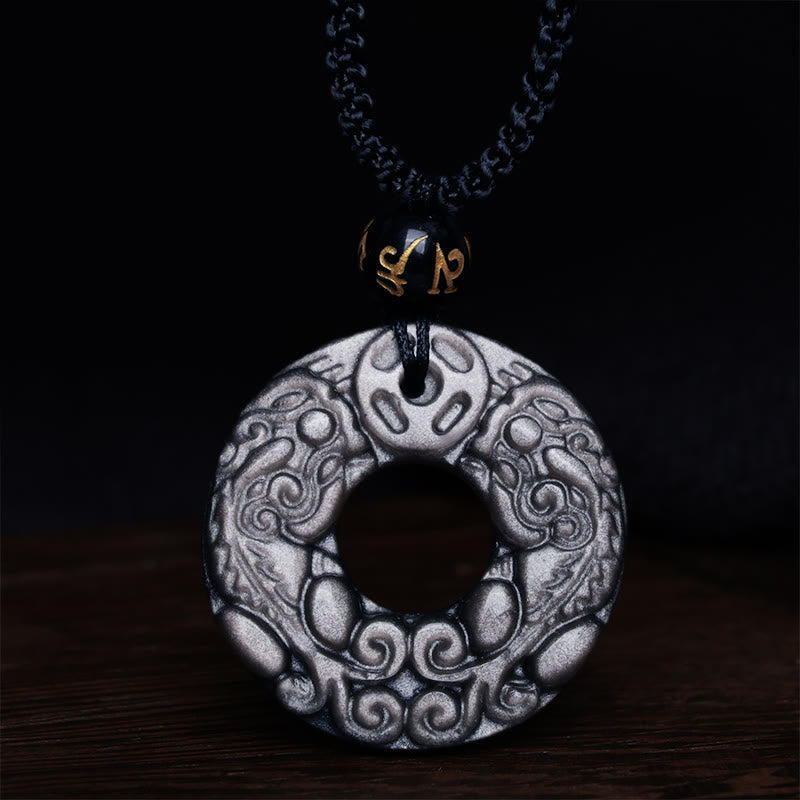 Silver Sheen Obsidian Double PiXiu Necklace – Close-up obsidian disc with cloud patterns on dark wood, energy necklace