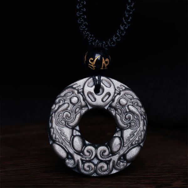 Silver Sheen Obsidian Double PiXiu Necklace – Close-up obsidian disc with cloud patterns on dark wood, energy necklace