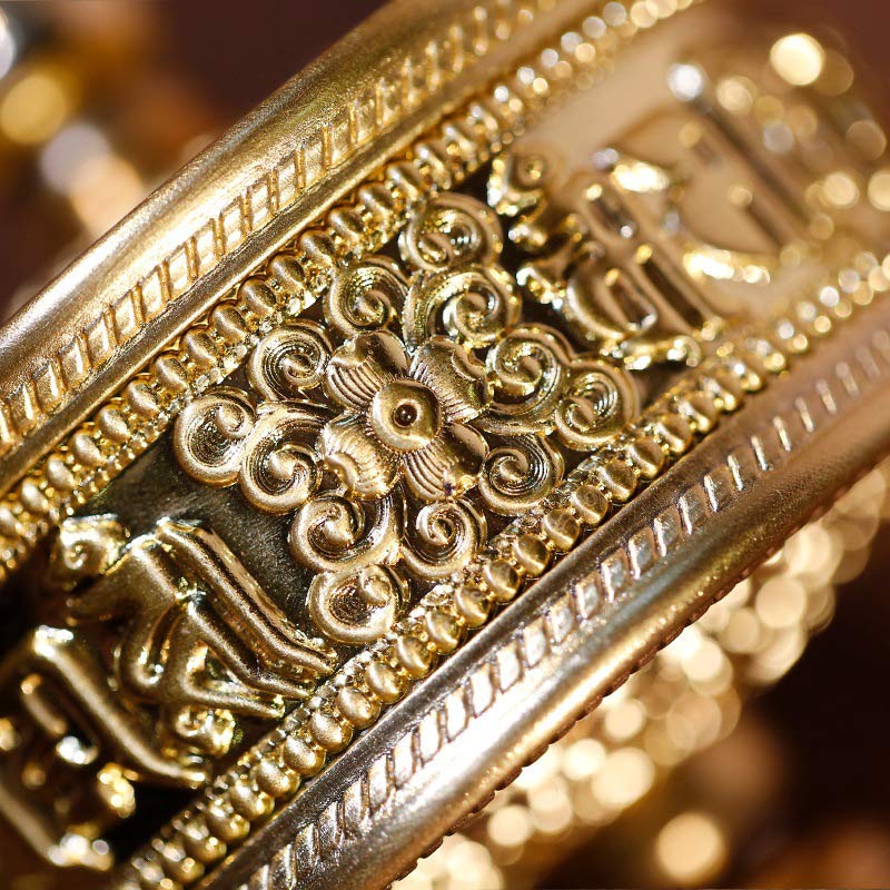 Sandalwood Tibetan Prayer Wheel – Close-up of golden brass body with lotus scrollwork and amber knob on carved wood displa...