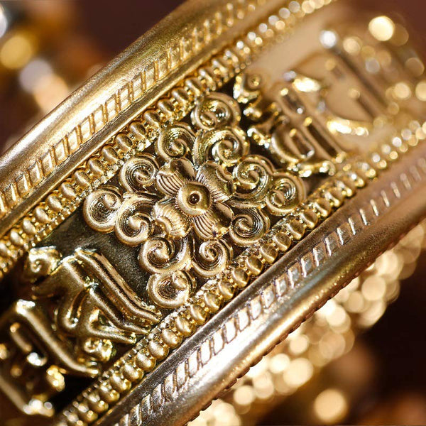 Sandalwood Tibetan Prayer Wheel – Close-up of golden brass body with lotus scrollwork and amber knob on carved wood displa...