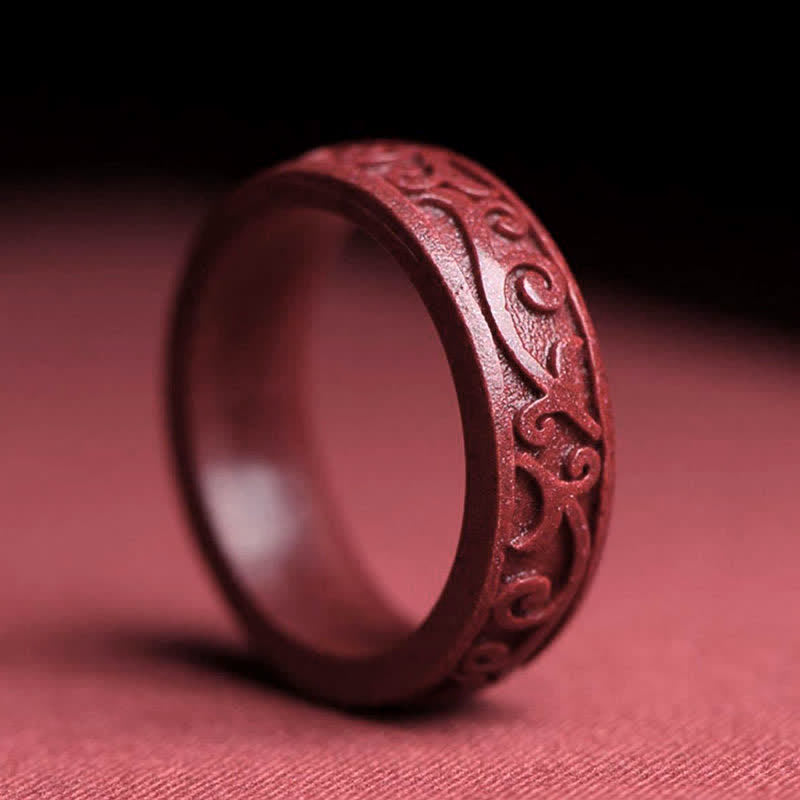 Cinnabar Om Mani Padme Hum Blessing Ring – carved cinnabar band with swirling vine and cloud scroll motifs, three-quarter side view