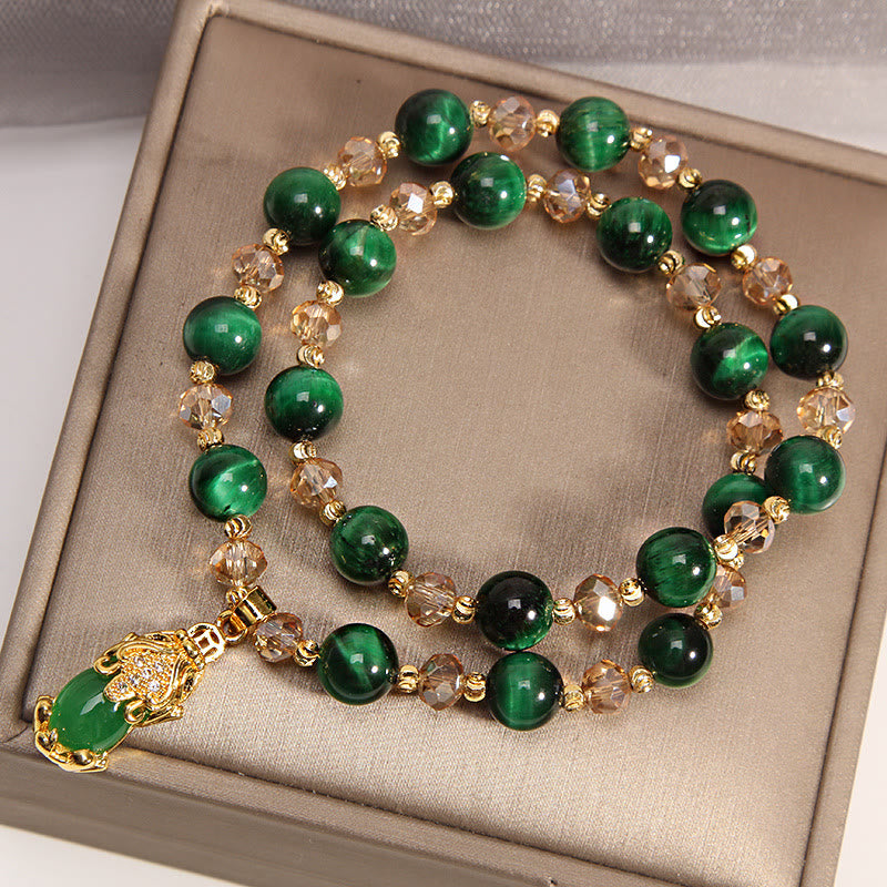 Tiger Eye Pixiu Fox Money Bag Bracelet - green tiger eye Pixiu charm double strand bracelet with gold crystal accents on champagne display surface, chatoyant green gemstone beads in feng shui design