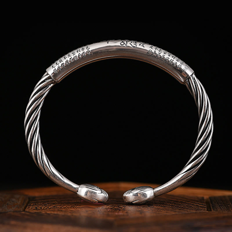 Tibetan Heart Sutra Cuff Bracelet – vertical frontal shot on black backdrop with wood base, spiral finial engraving