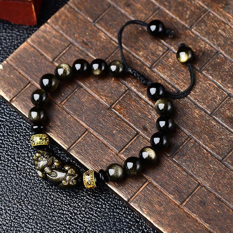 Gold Sheen Obsidian Pixiu Bracelet – Flat lay on wood and leather showing golden flash beads, feng shui