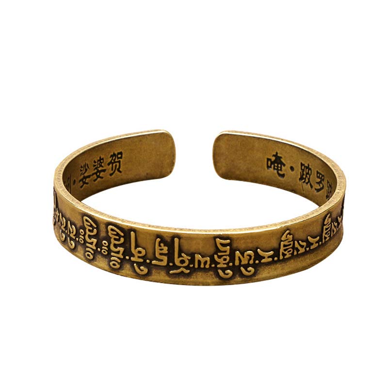 Antique brass mantra cuff bracelet with embossed Sanskrit Tibetan script and interior Chinese Om mantra characters on white background