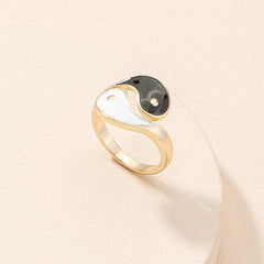 Yin Yang Adjustable Couple Ring - angled view of gold black white enamel symbol on cream surface, balance jewelry