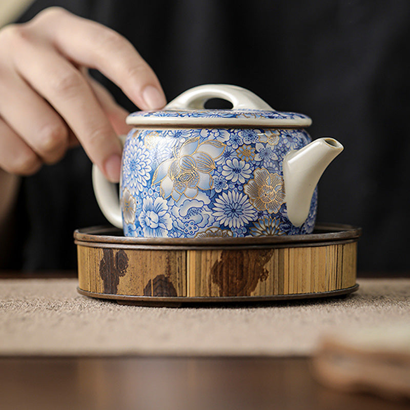 Lotus Chrysanthemum Ceramic Teapot - Hand on lid over artisan wooden stand, ceremonial serving