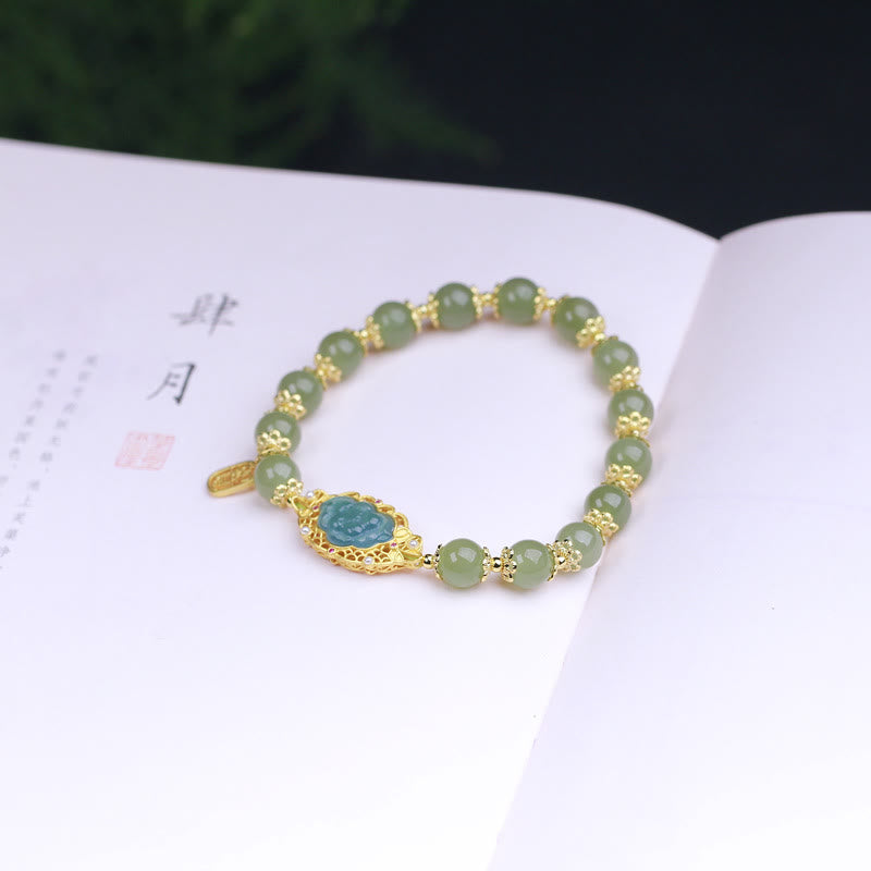 Hetian Jade Lotus Bracelet - resting on calligraphy book with carved blue-green lotus center, jade bead bracelet